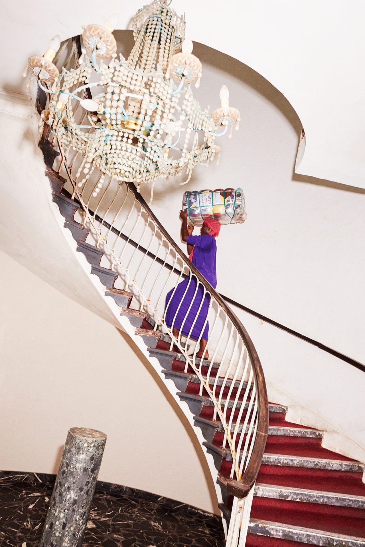 Asana carries a bale of clothing while ascending the grand stairs in Osu Castle in Accra Ghana by Charlie Engman