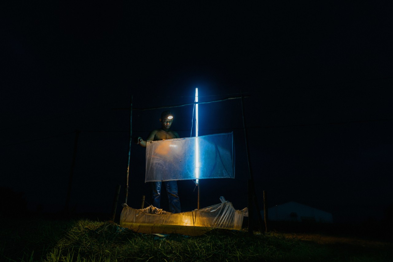 Chu Sopheak lights a cricket trap in Kampong Thom Cambodia by Rishabh Malik