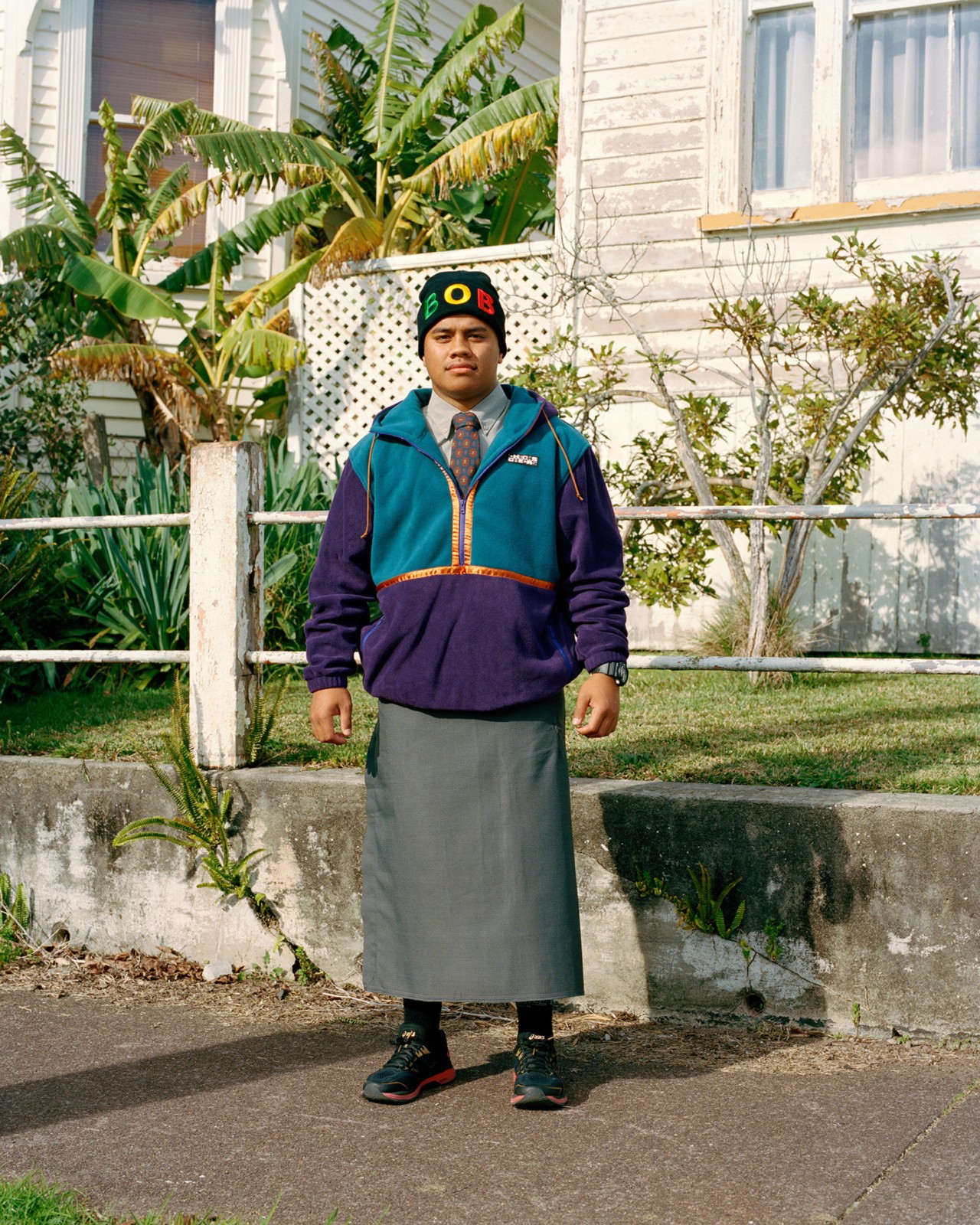 A teenage boy wears a mix of traditional and international clothing in Auckland New Zealand by Derek Henderson