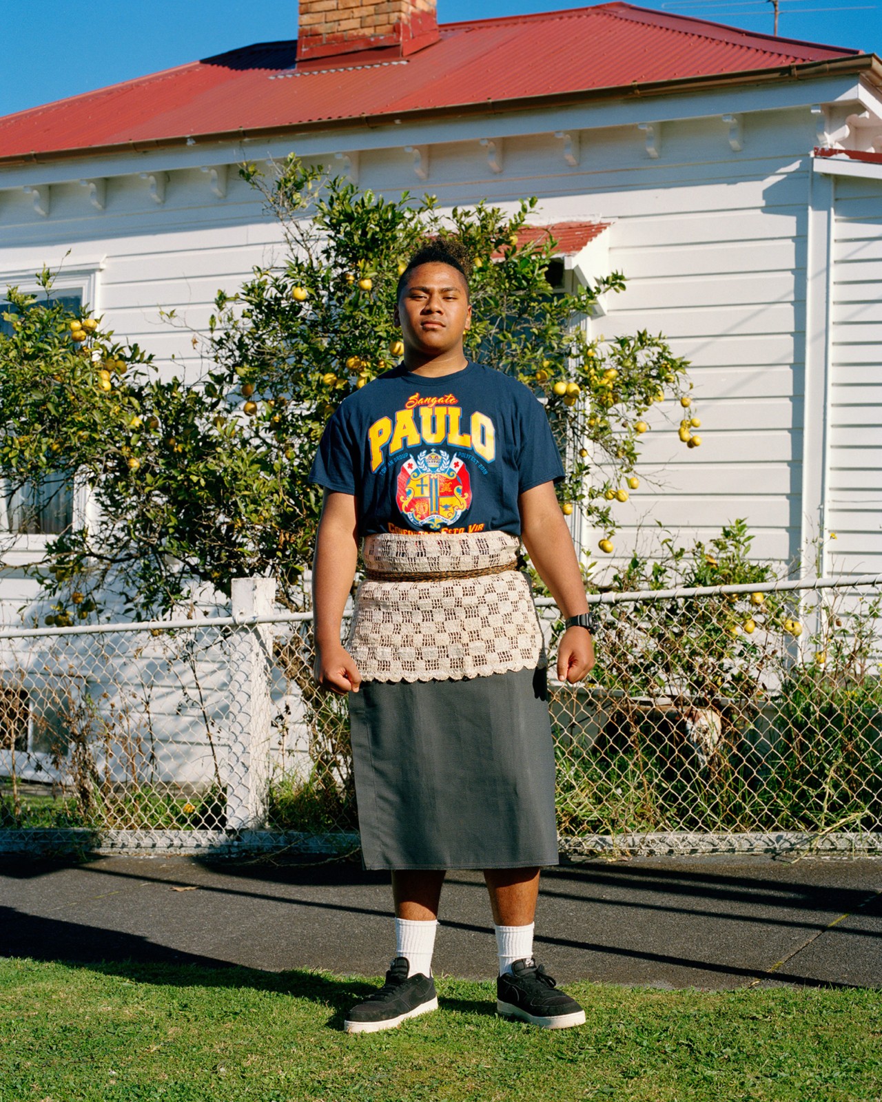 A teenage boy wears a mix of traditional and international clothing in Auckland New Zealand by Derek Henderson