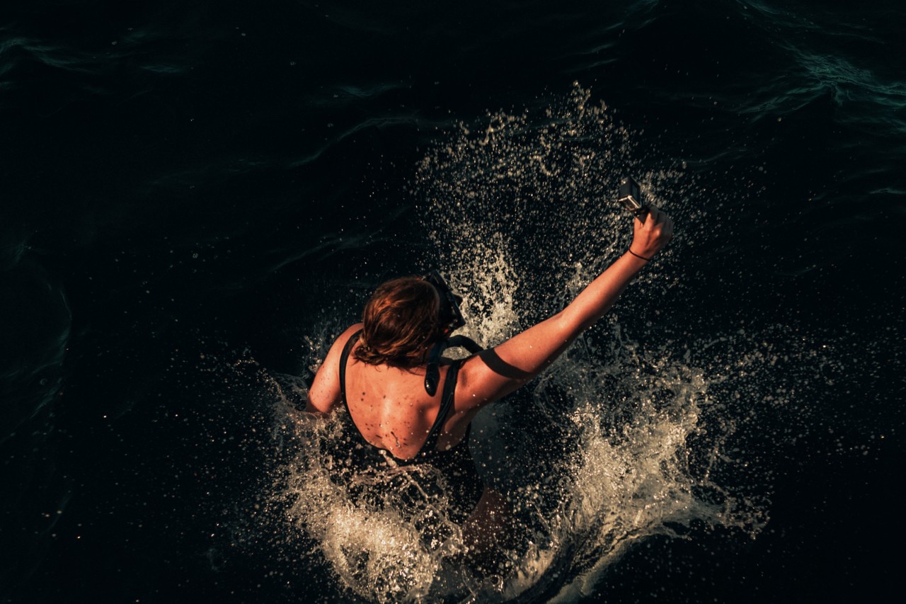 Woman taking selfie while jumping in water by Rishabh Malik