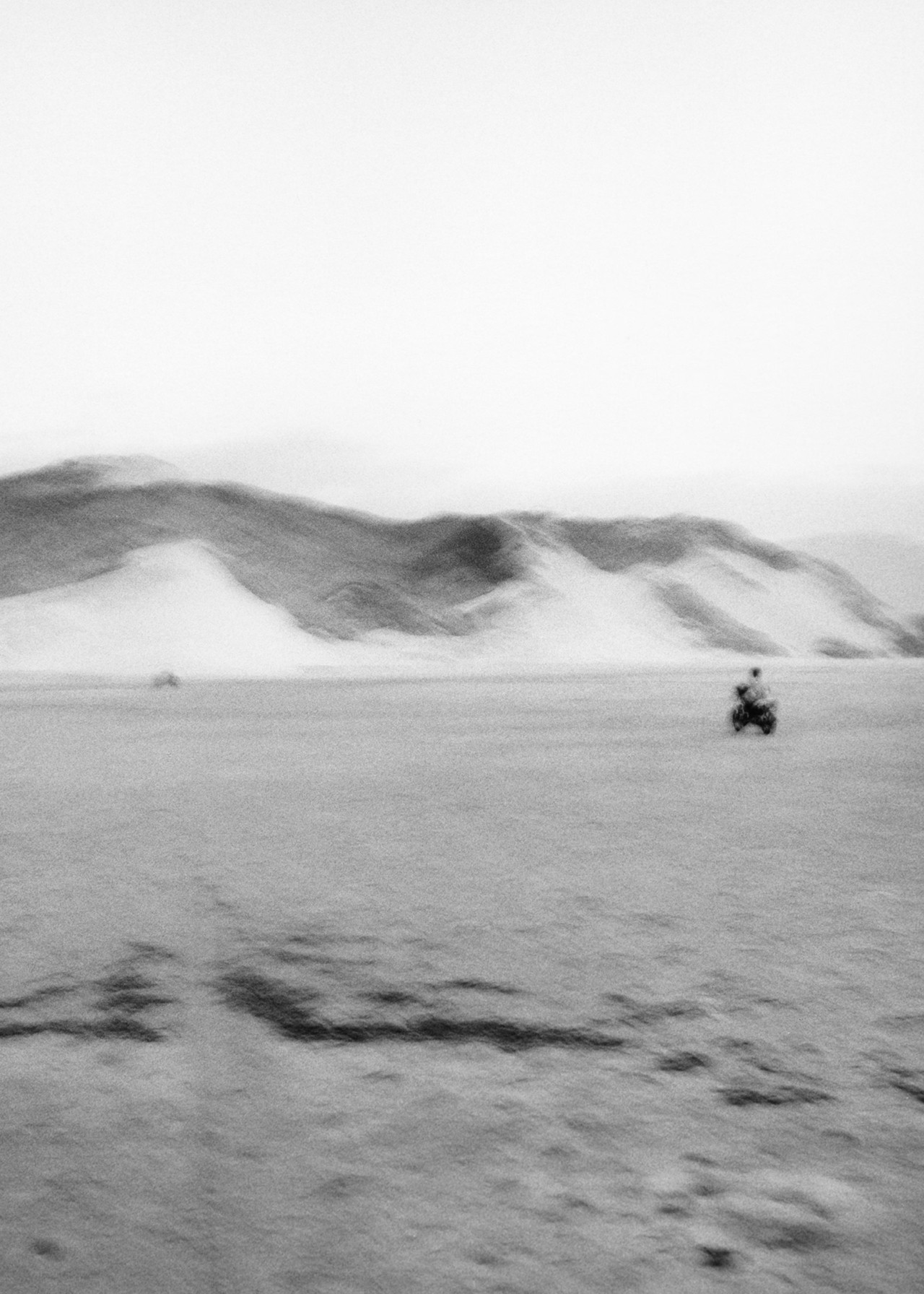 A person rides a motorcycle in the desert in Socotra Yemen by Jamie Hawkesworth
