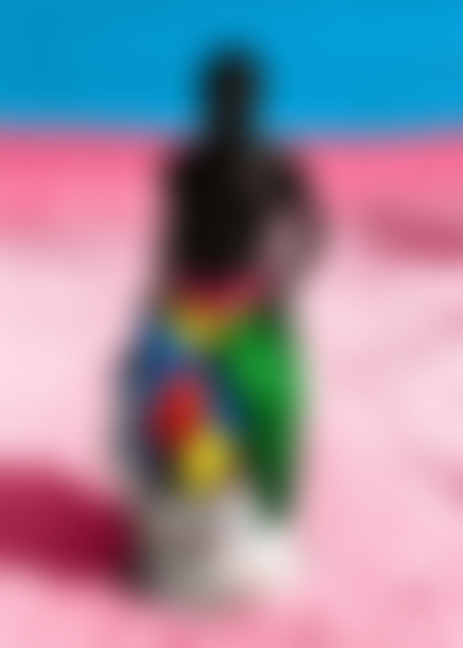 A boy carries a sack full of clothes along a pink sandy beach.
