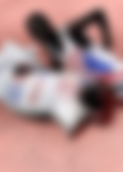 A boy wearing an american flag t-shirt lays down next to a large sack of clothes.