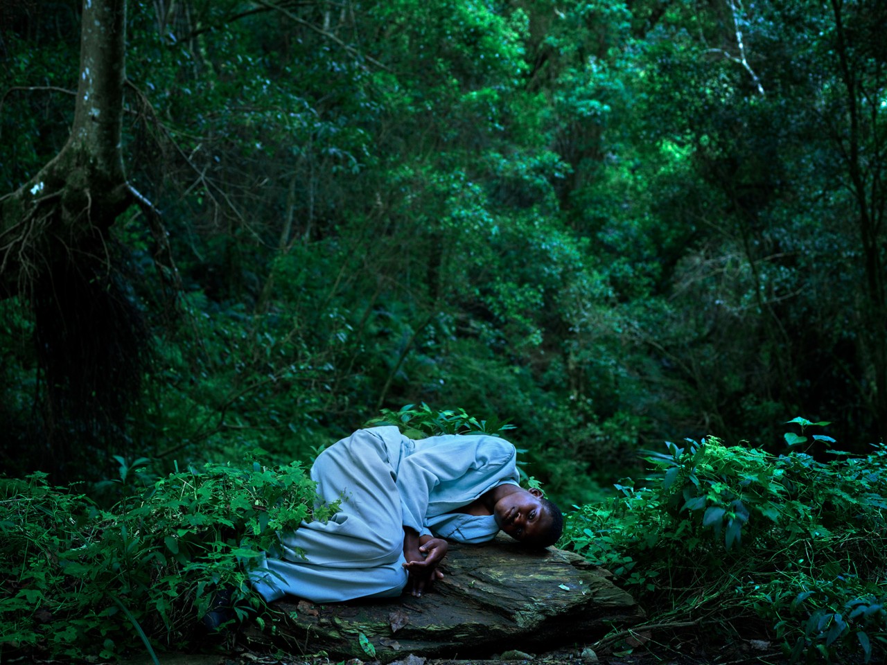 Child laying down in forest by Pieter Hugo