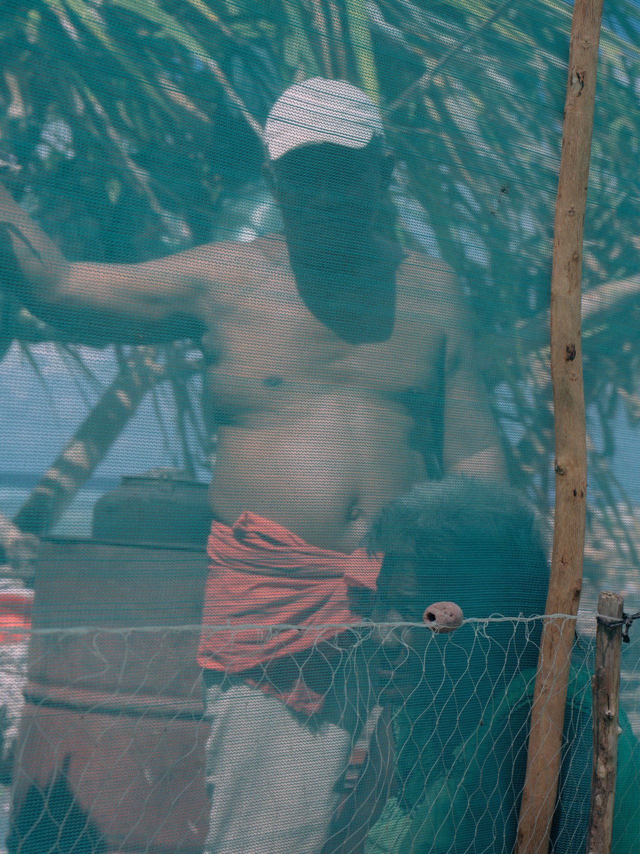 Kiribati man and woman standing behind netting by Will Warasila