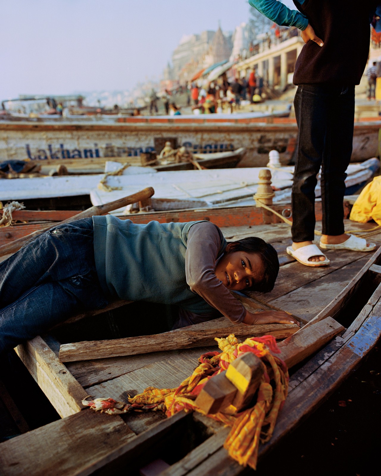 Person laying in a boat on the Ganges River in India by Ashish Shah