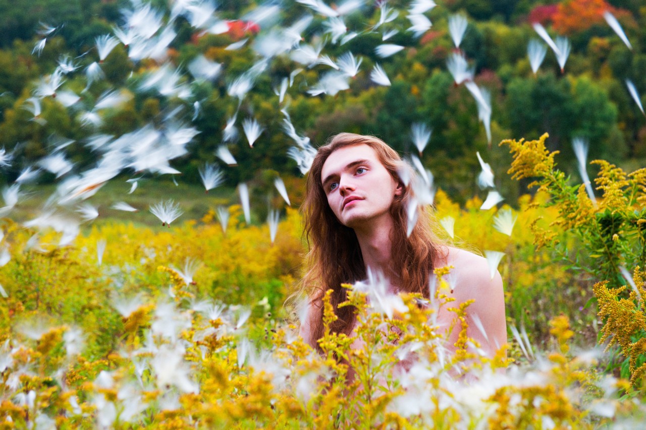 Man in yellow flower field by Ryan McGinley
