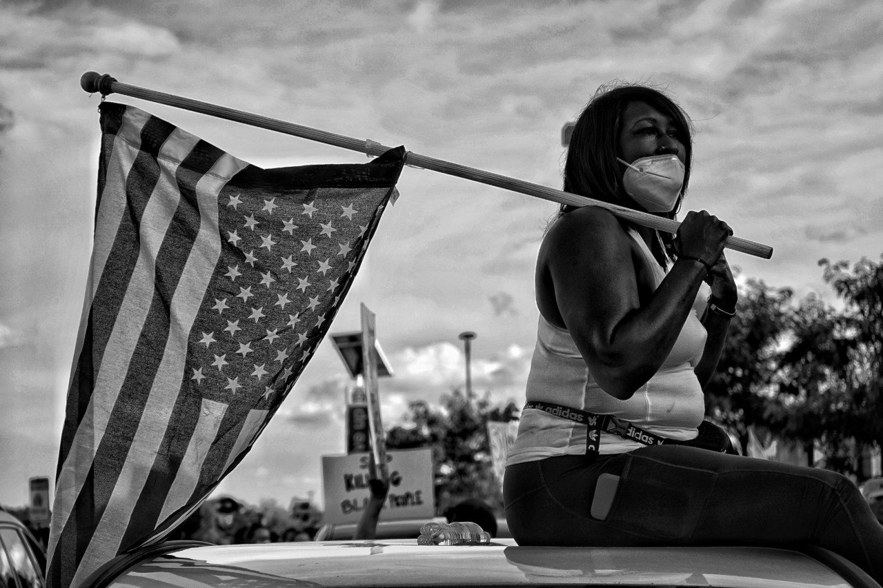 Woman at Black Lives Matter protest with American flag by Vanessa Charlot
