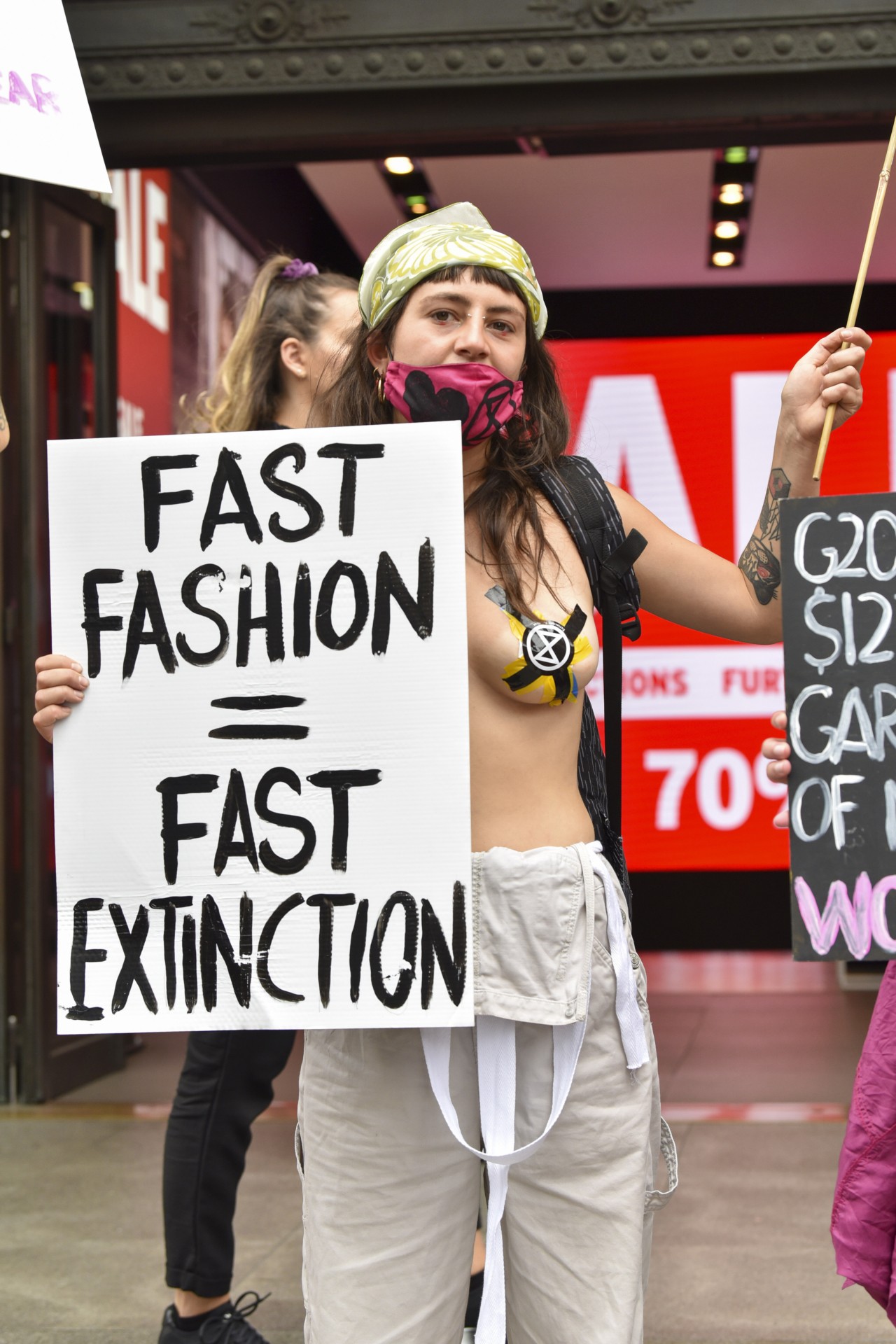 Extinction Rebellion activist holding a placard saying, Fast Fashion = Fast Extinction, during the Redress the Injustice Protest