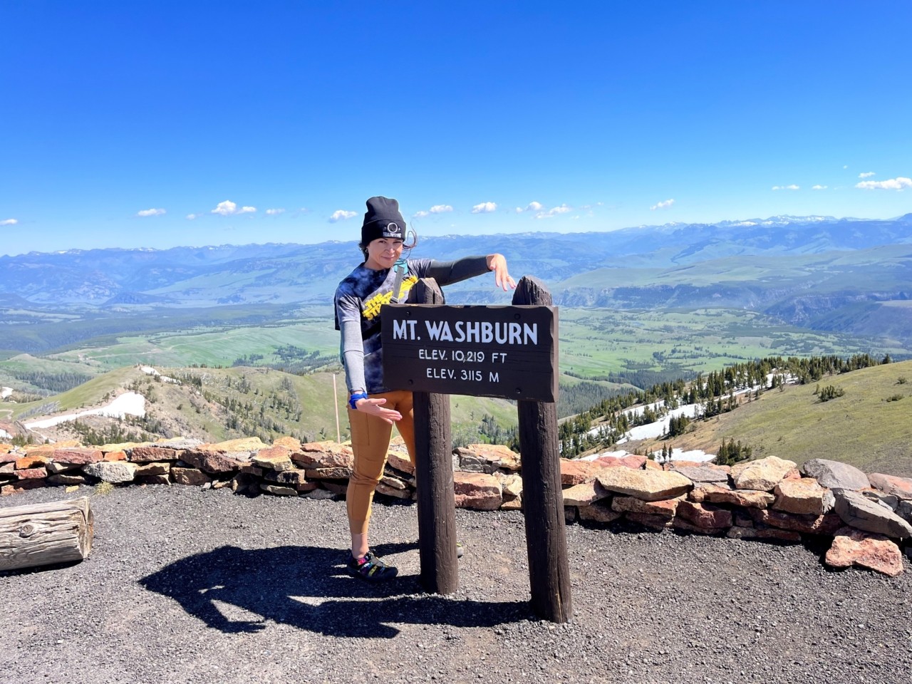 Ruth H. Burns standing on top of a mountain in front of a Mt. Washburn sign.