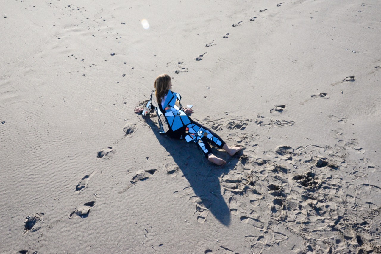 Tamara Lindeman/The Weather Station on the beach in a mirror suit by Rima Sater