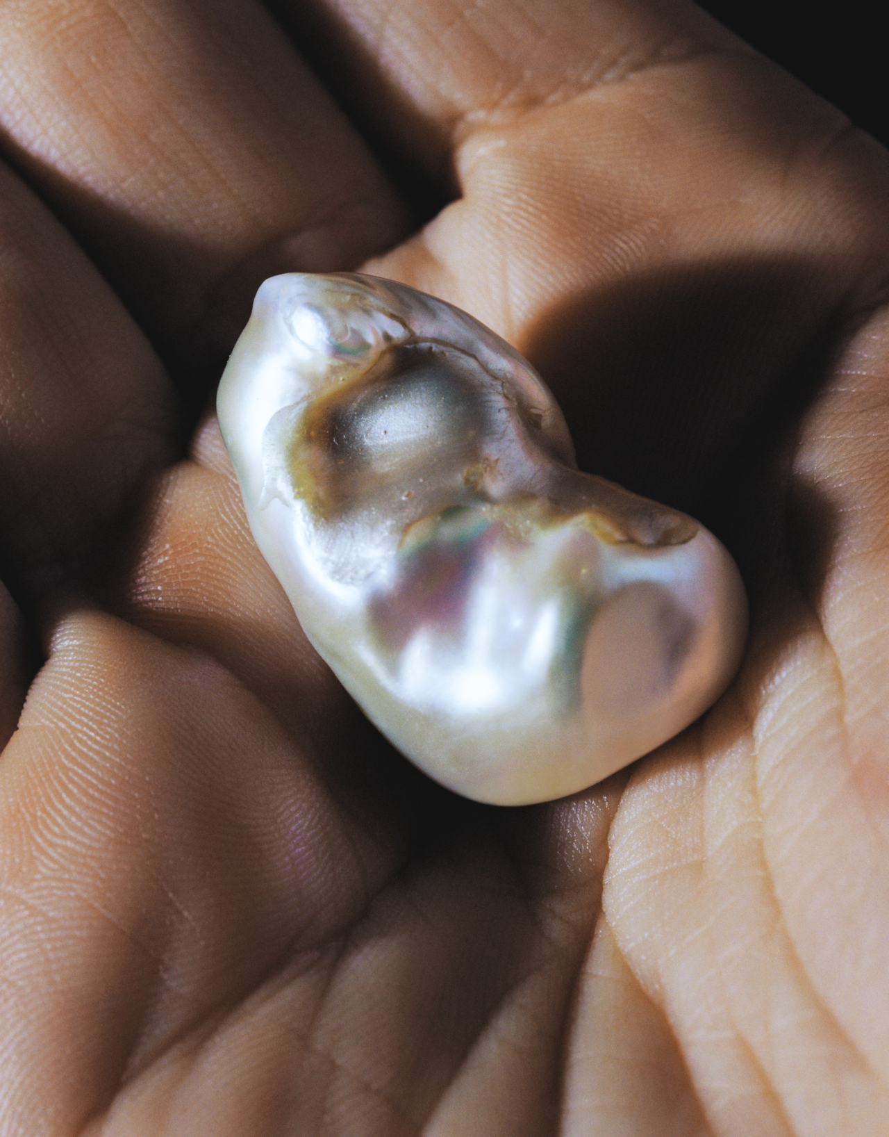 A shiny pearl rest in the palm of someone's hand.