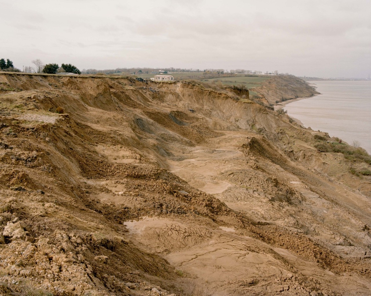 Eroded, dirt cliff along British coastline exemplifies geological erosion and land loss in British isles.