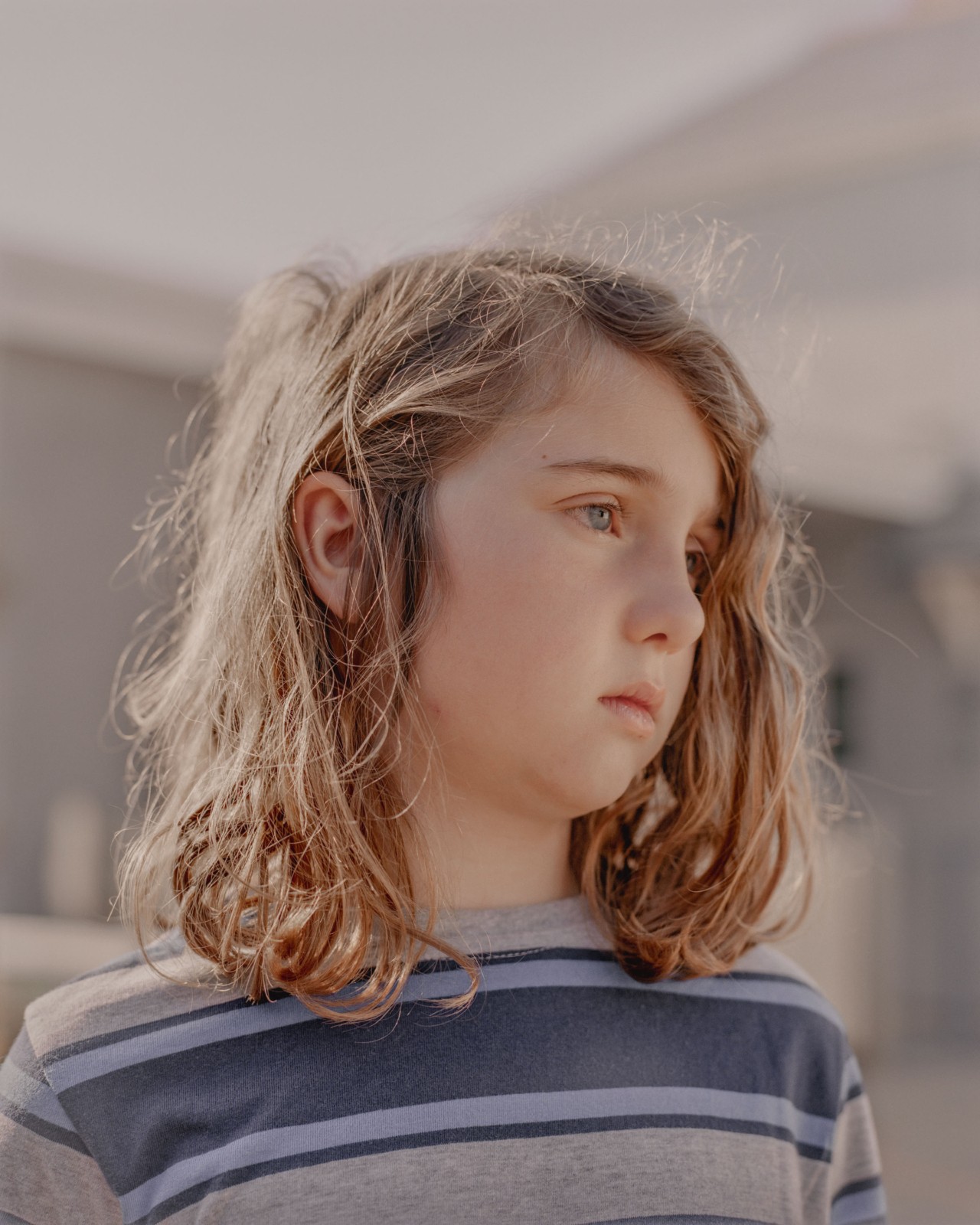 A young, blonde girl in the British east coast looks away with a sad expression.