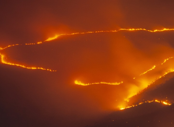 Top view of a wildfire as it forms a circular shape and ravages land.