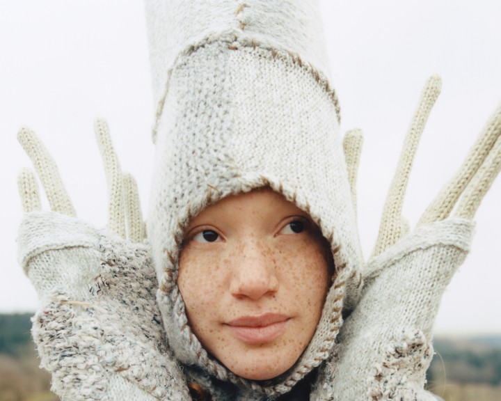 A young woman wears a white costume.