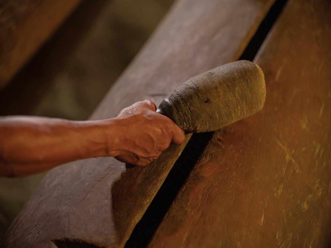 The arm of a person grasping onto a large drummer stick in the Amazon rainforest.