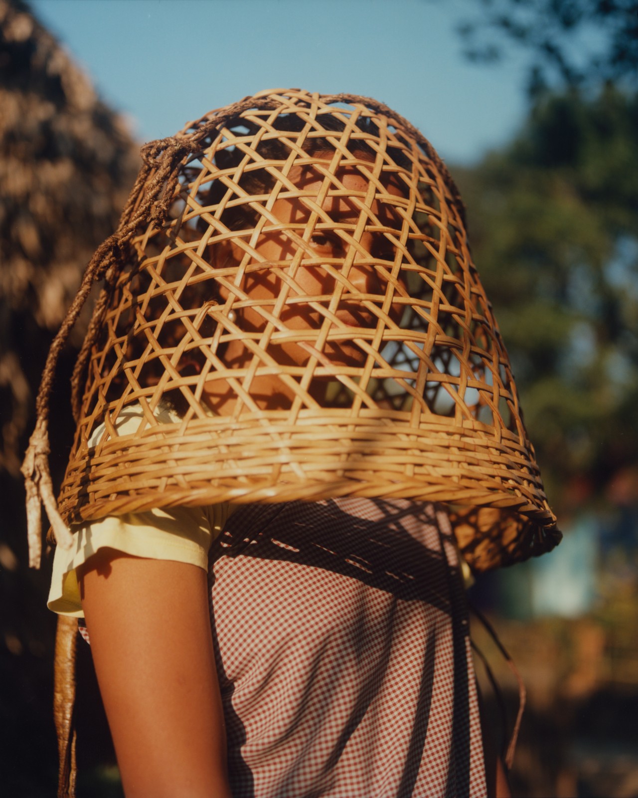 A young person wearing a basket on their head looks toward the camera.