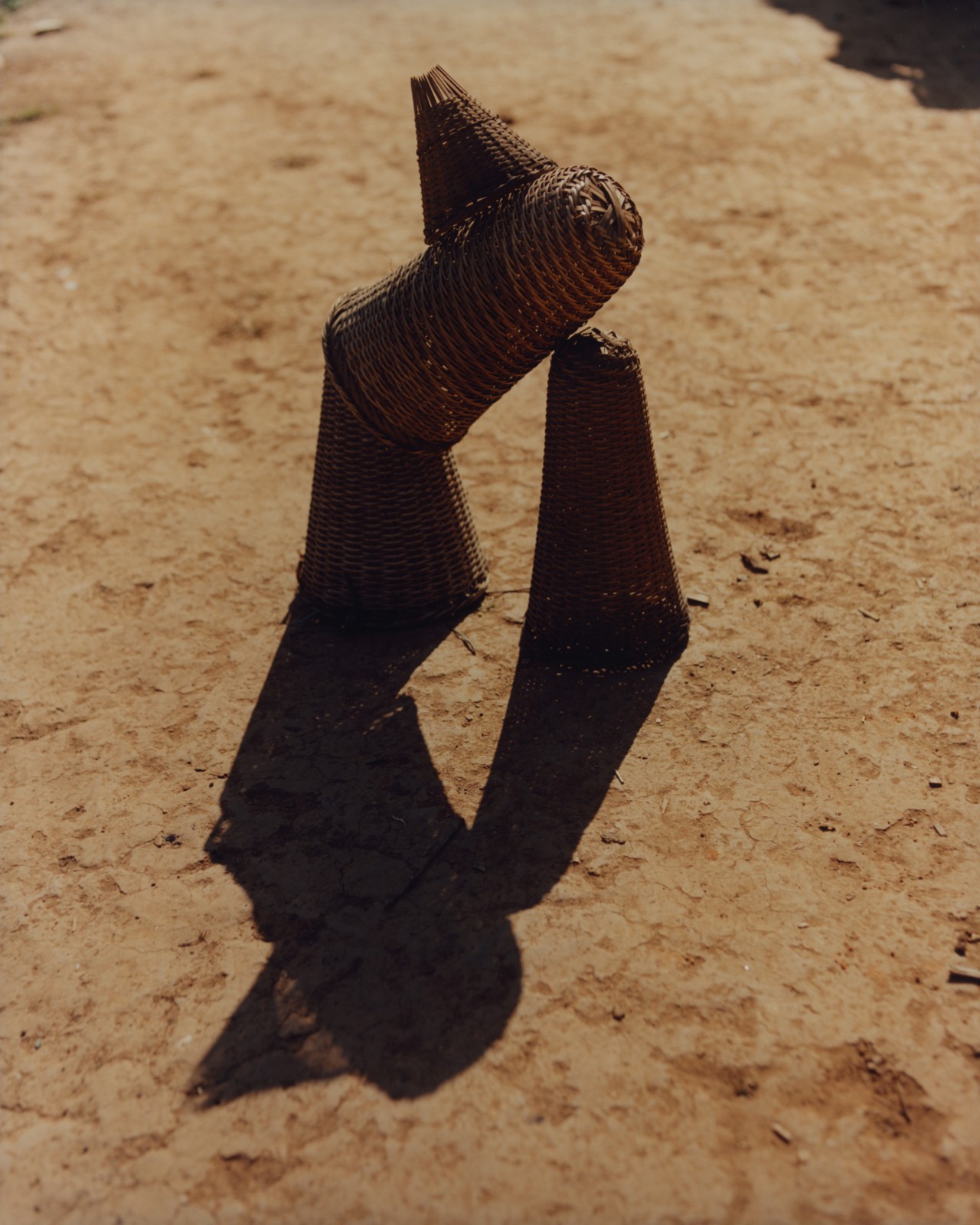Small woven wooden baskets are stacked on the desert ground.
