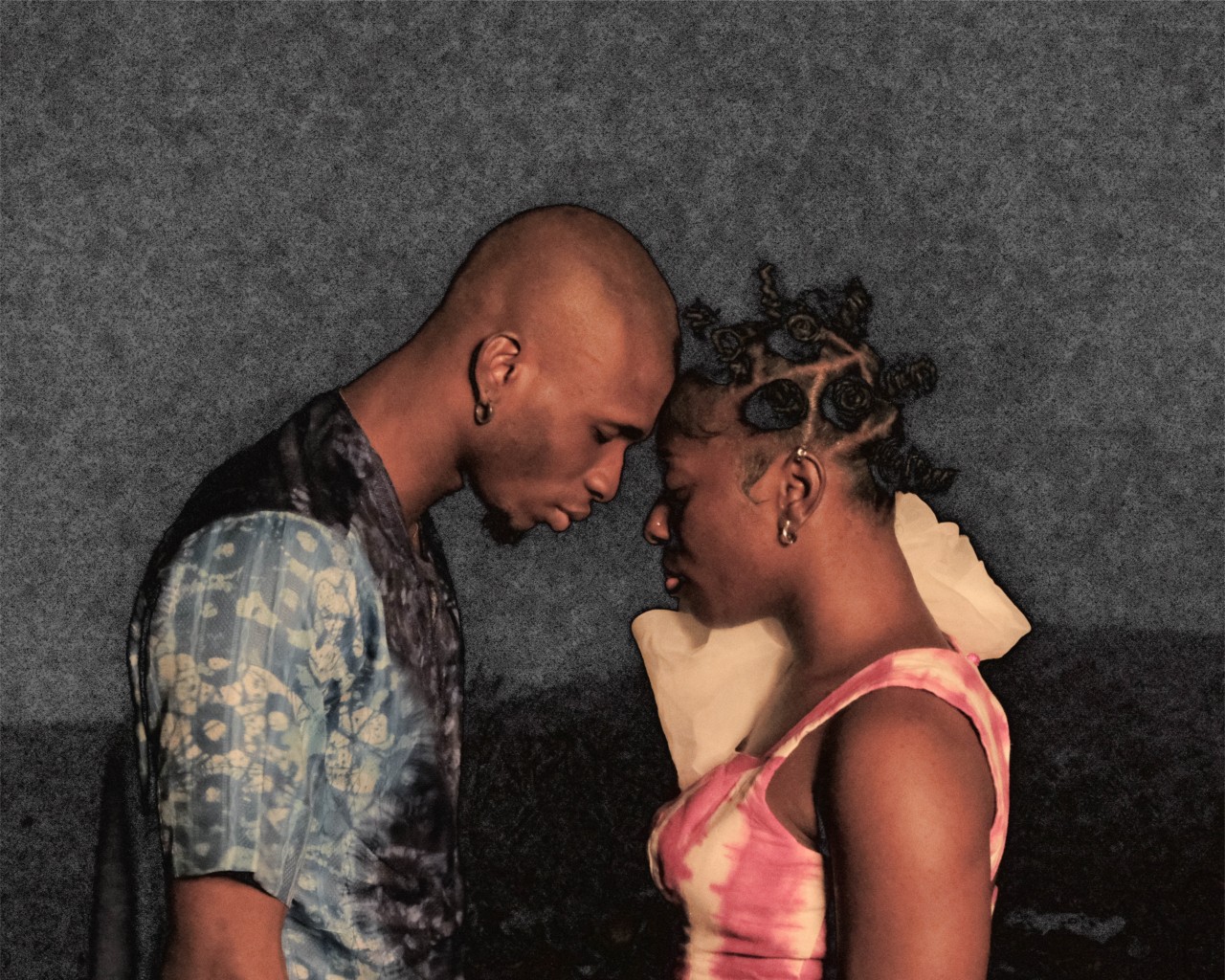 Two lovers lean their foreheads against one another beneath the moon.