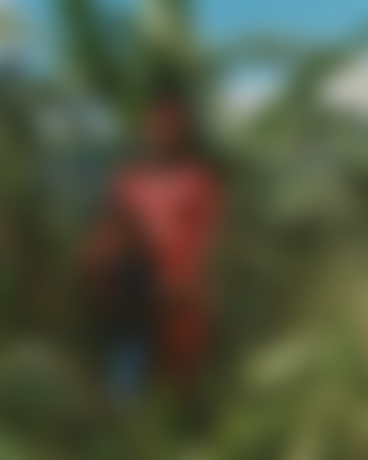 A Jamaican woman and a young buy stand next to each other amidst the jungles of Jamaica.