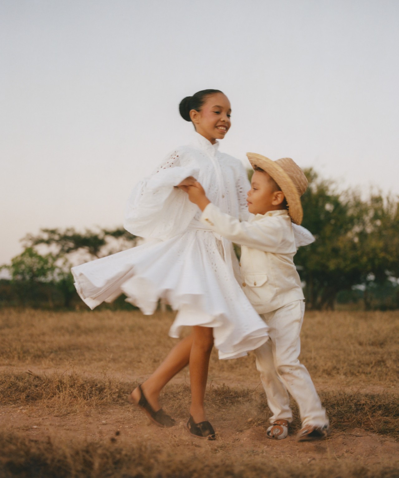 A young Venezuelan girl and a little boy dance together on the plains of Venezuela.