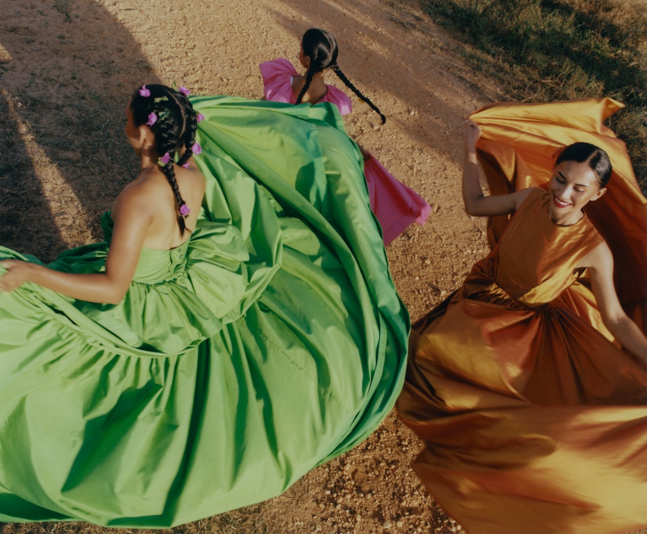 Three Venezuelan dancers dressed in colorful dresses are in mid dance on the plains of Venezuela.