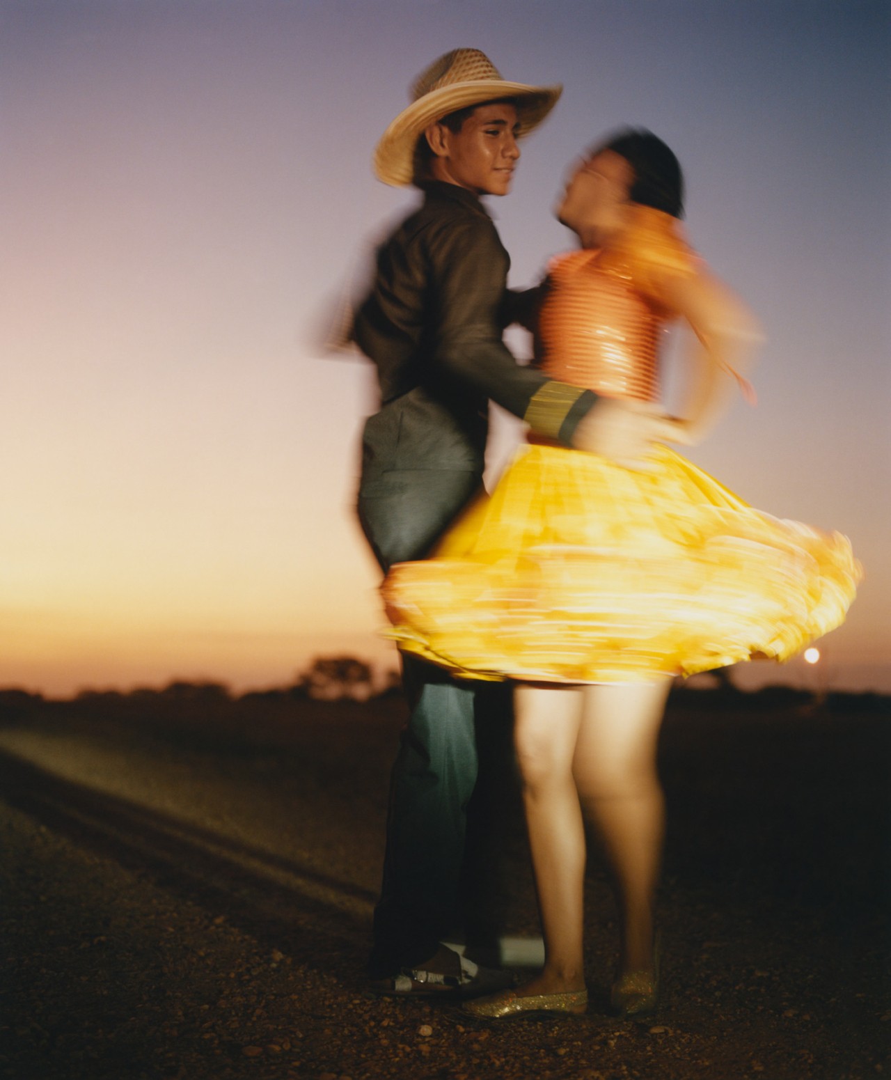 Two Venezuelan dancers are in mid dance on the plains of Venezuela.