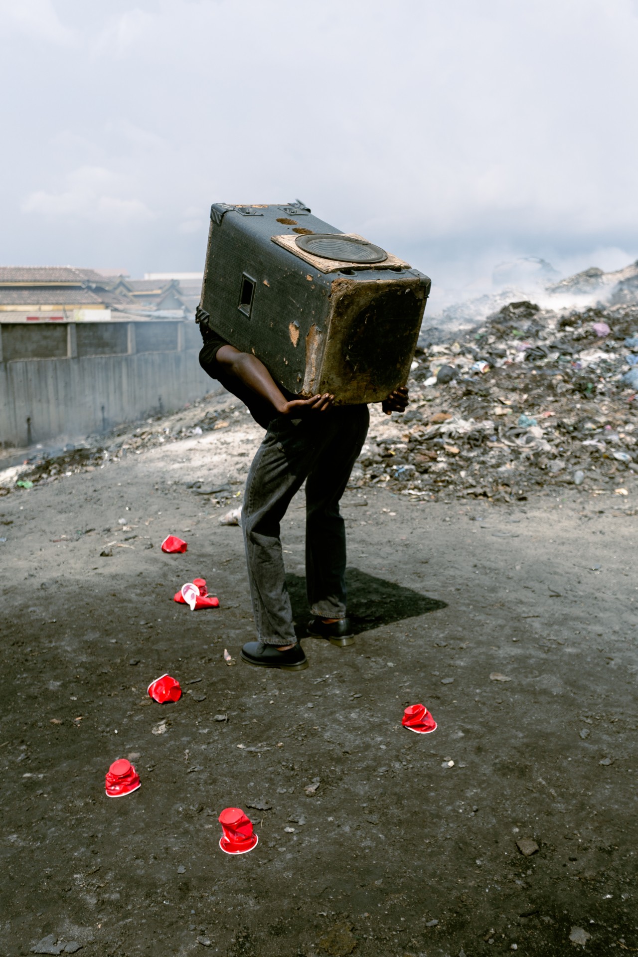 A man carries a speaker box on his back in a junkyard