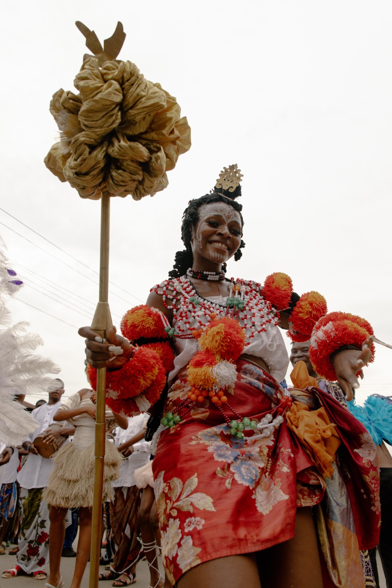A carnival performer smiles while dressed in a flamboyant costume.