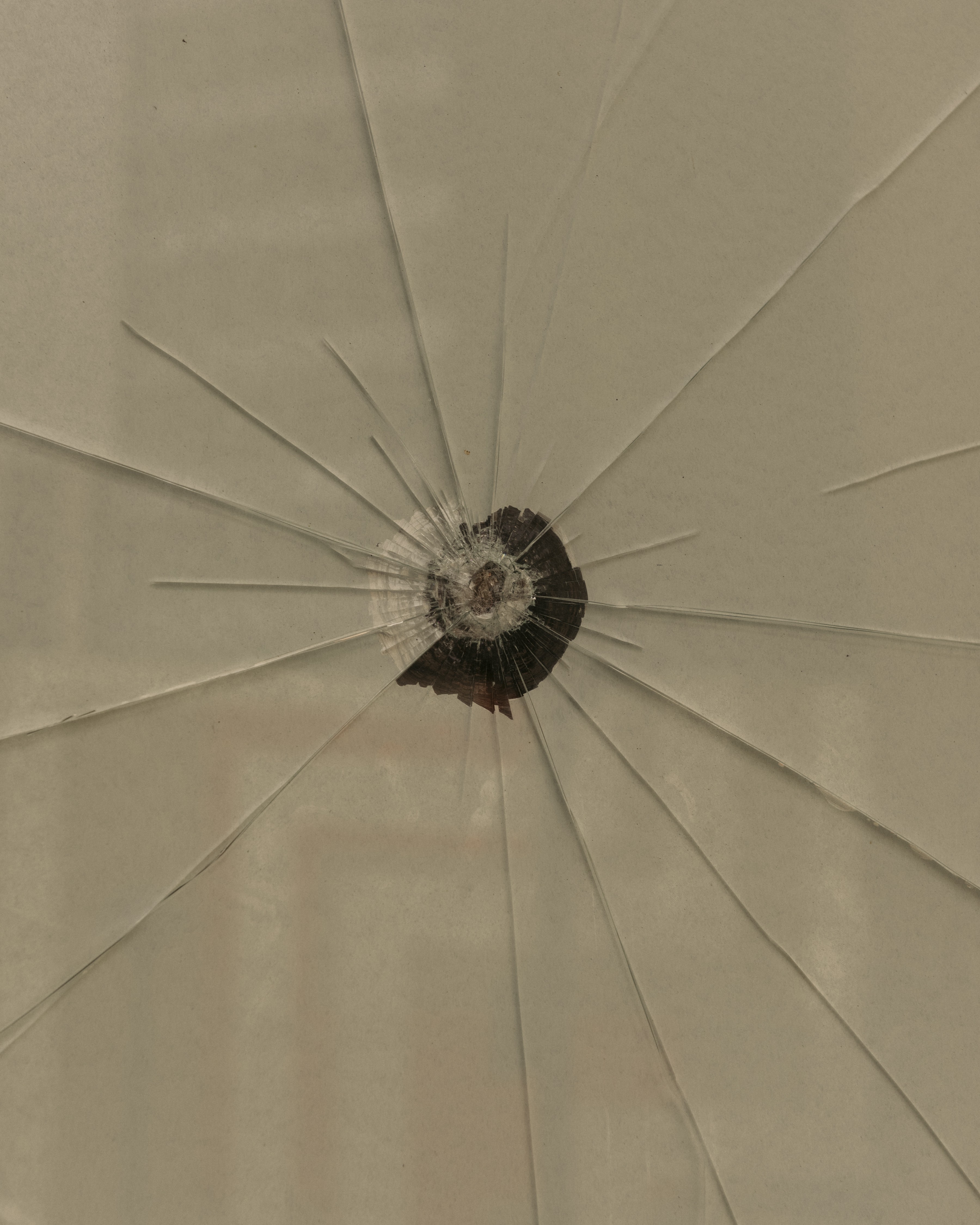 A bullet fractures a glass window.