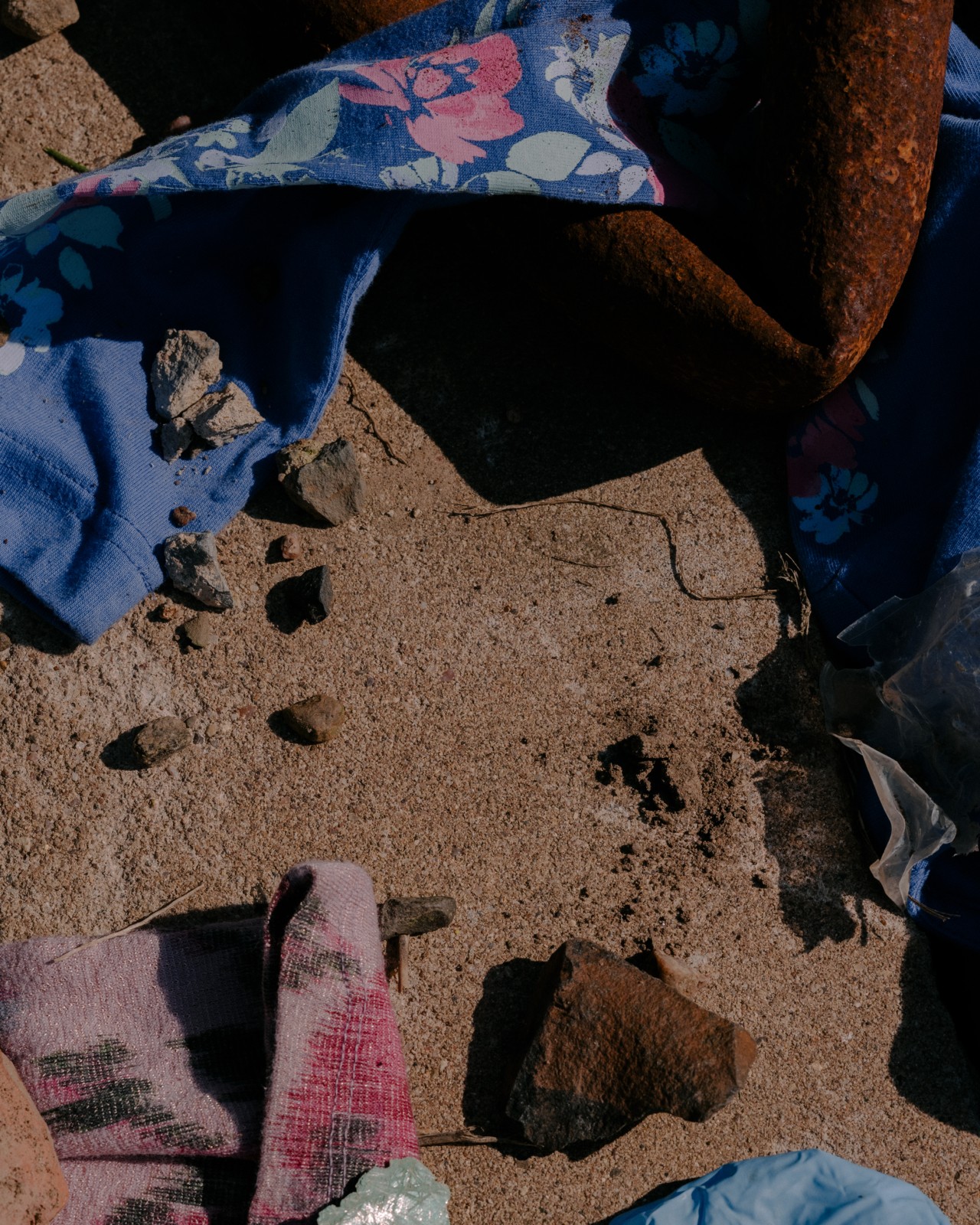 Garments are slightly buried beneath rocks and sand.