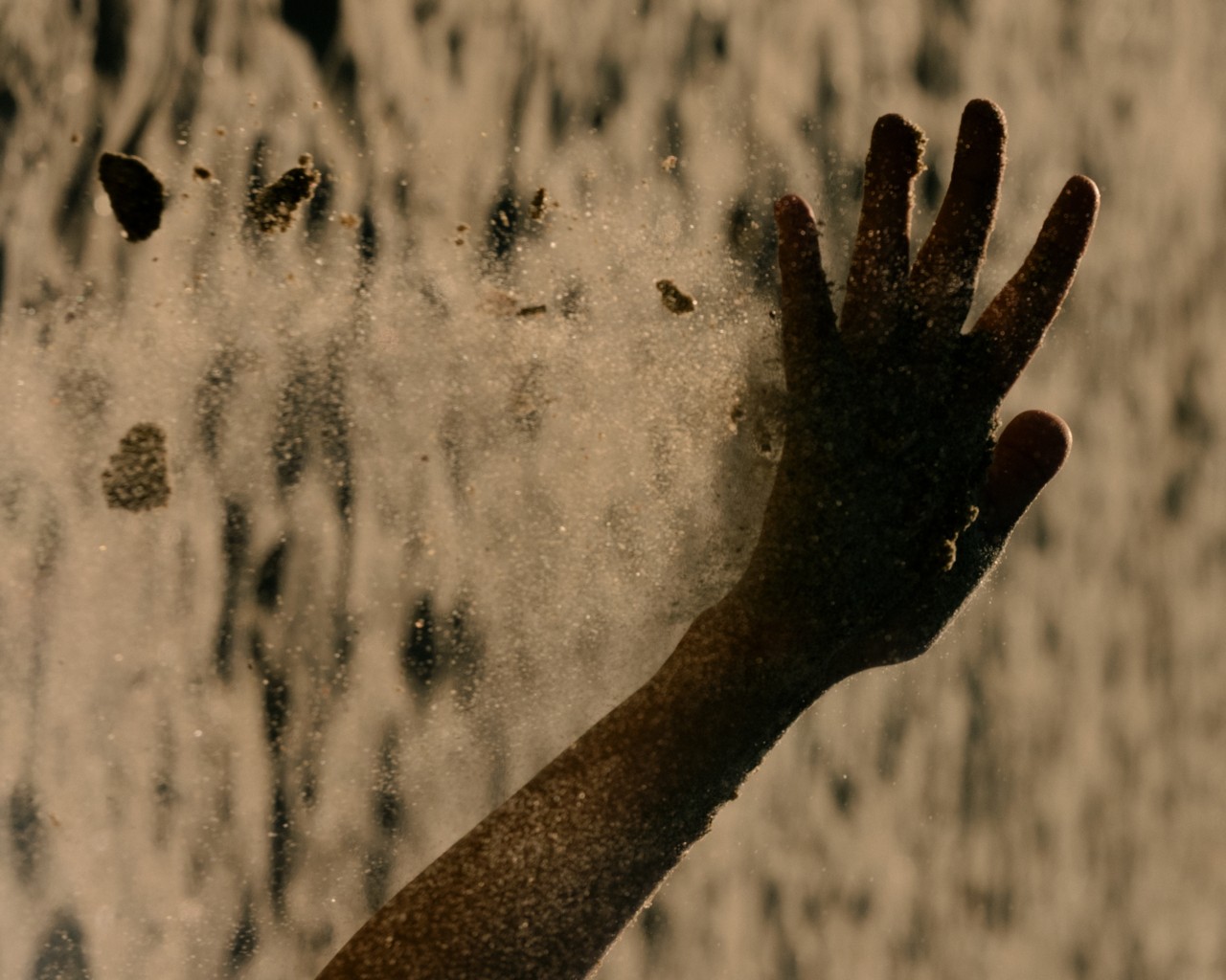 Dust particles fall off a shadowed human hand