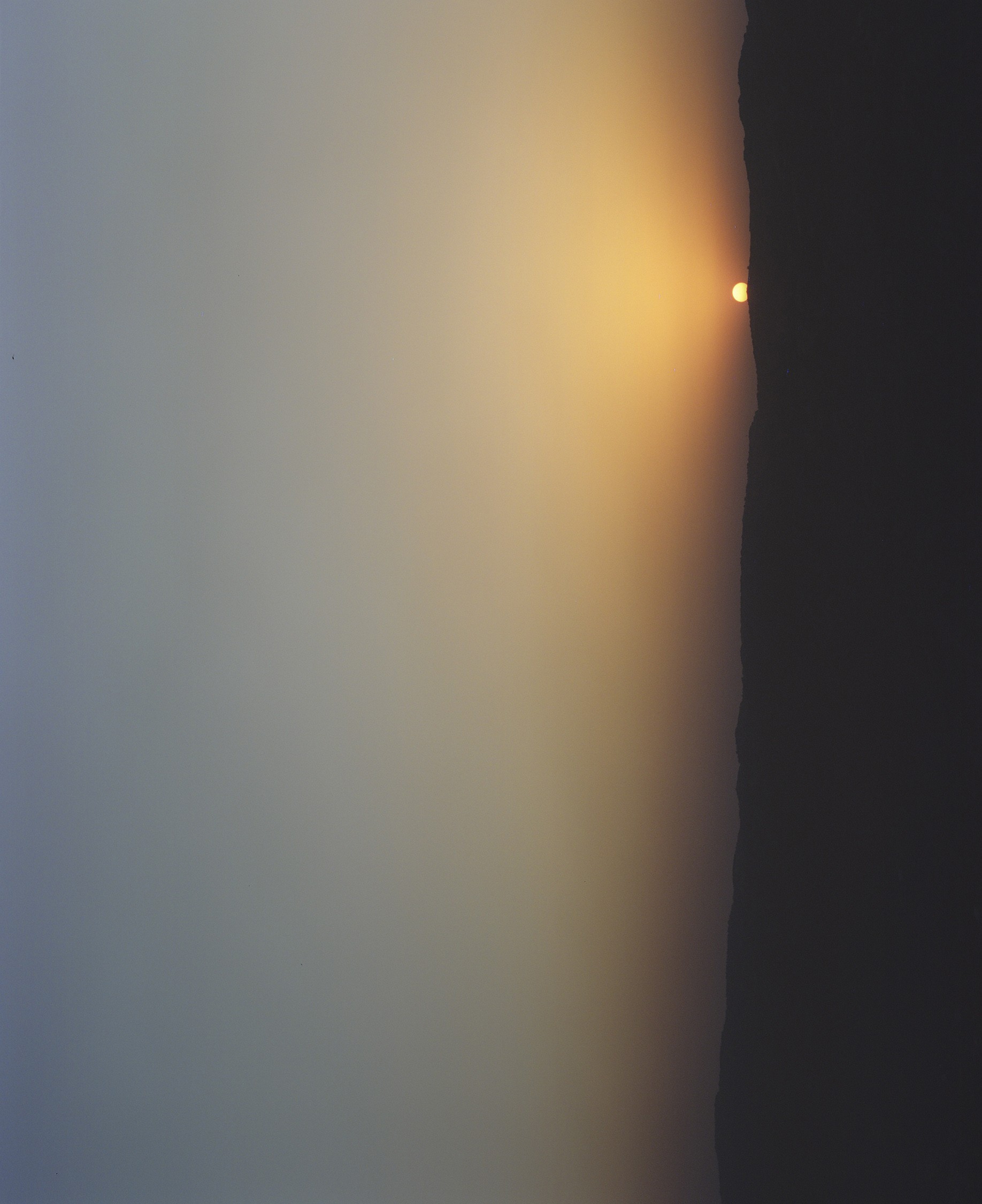 Orange sun partially shown in the distance setting along the hazy horizon.