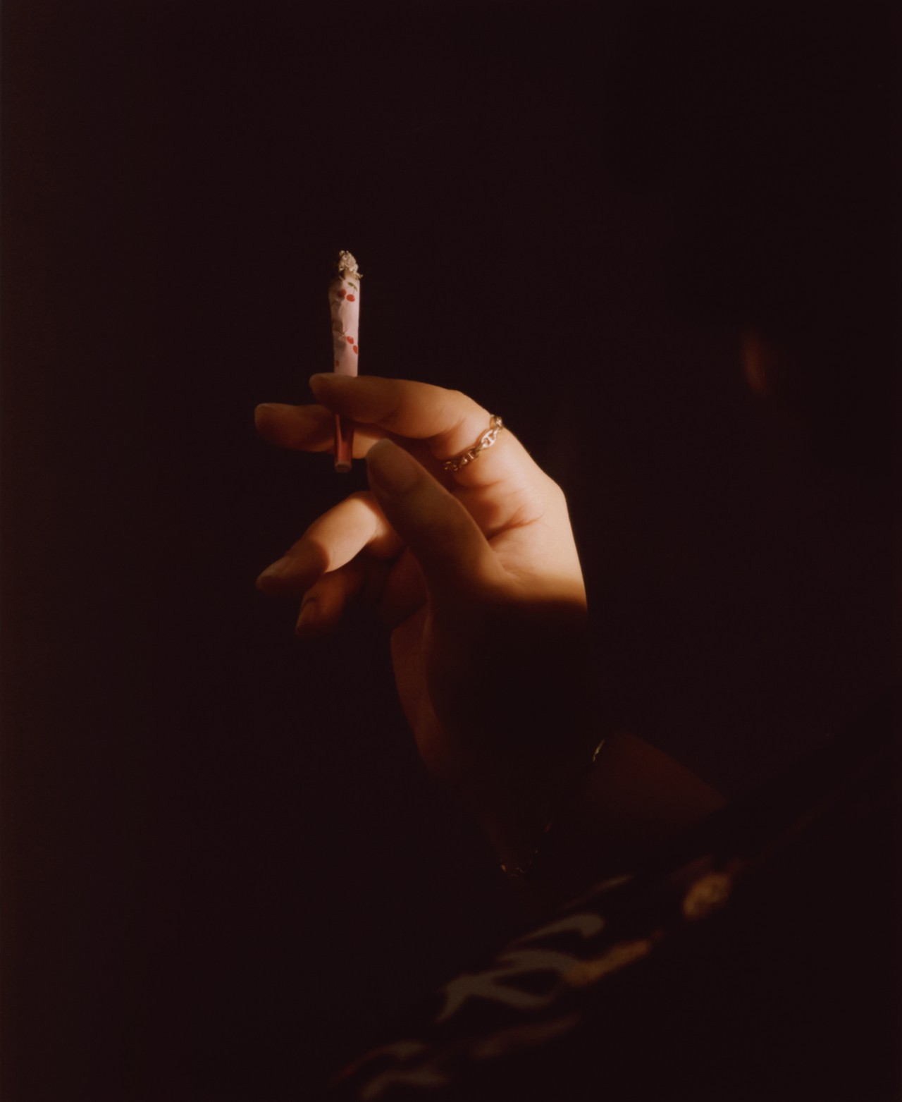 The hand of a teenager holding a blunt in the shadows