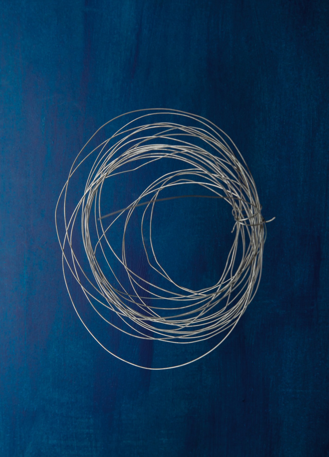 A bunch of wire is arranged in a circle. It sits in front of a blue background.