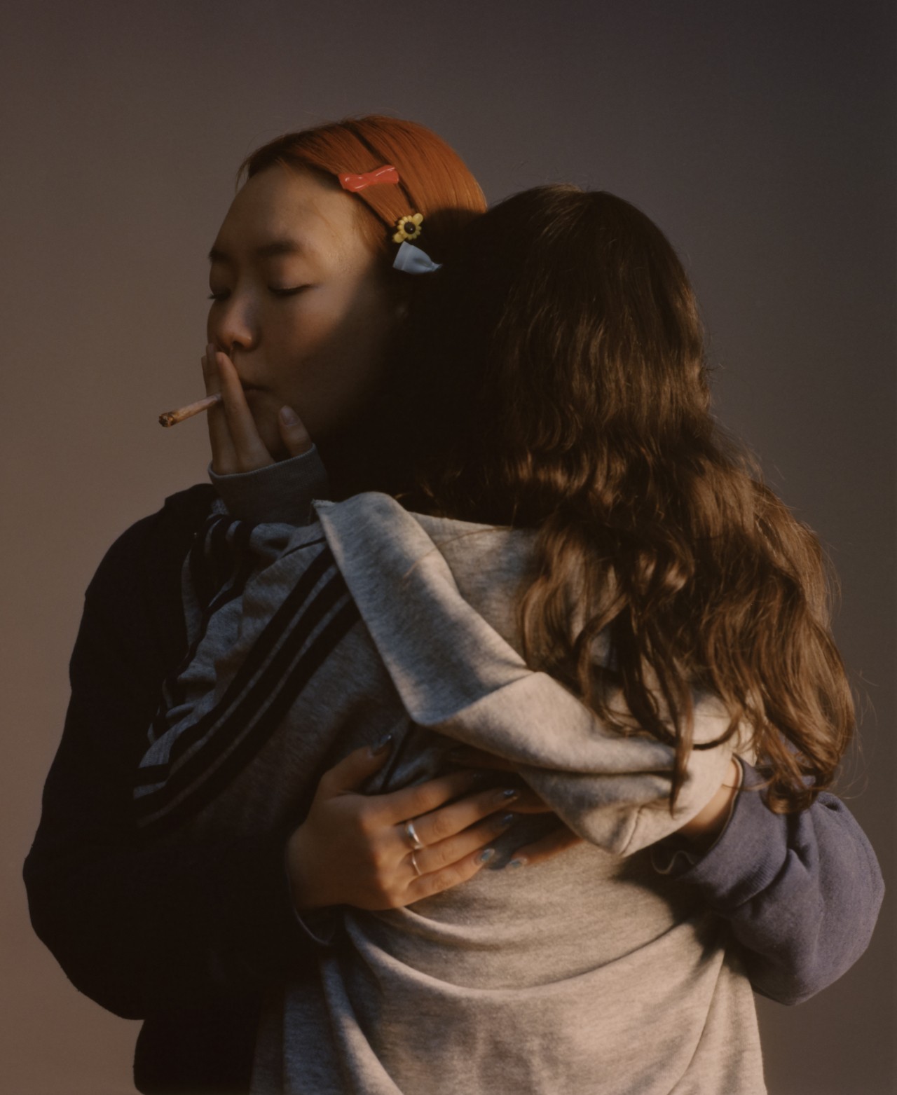 Two teenagers hug while smoking a blunt