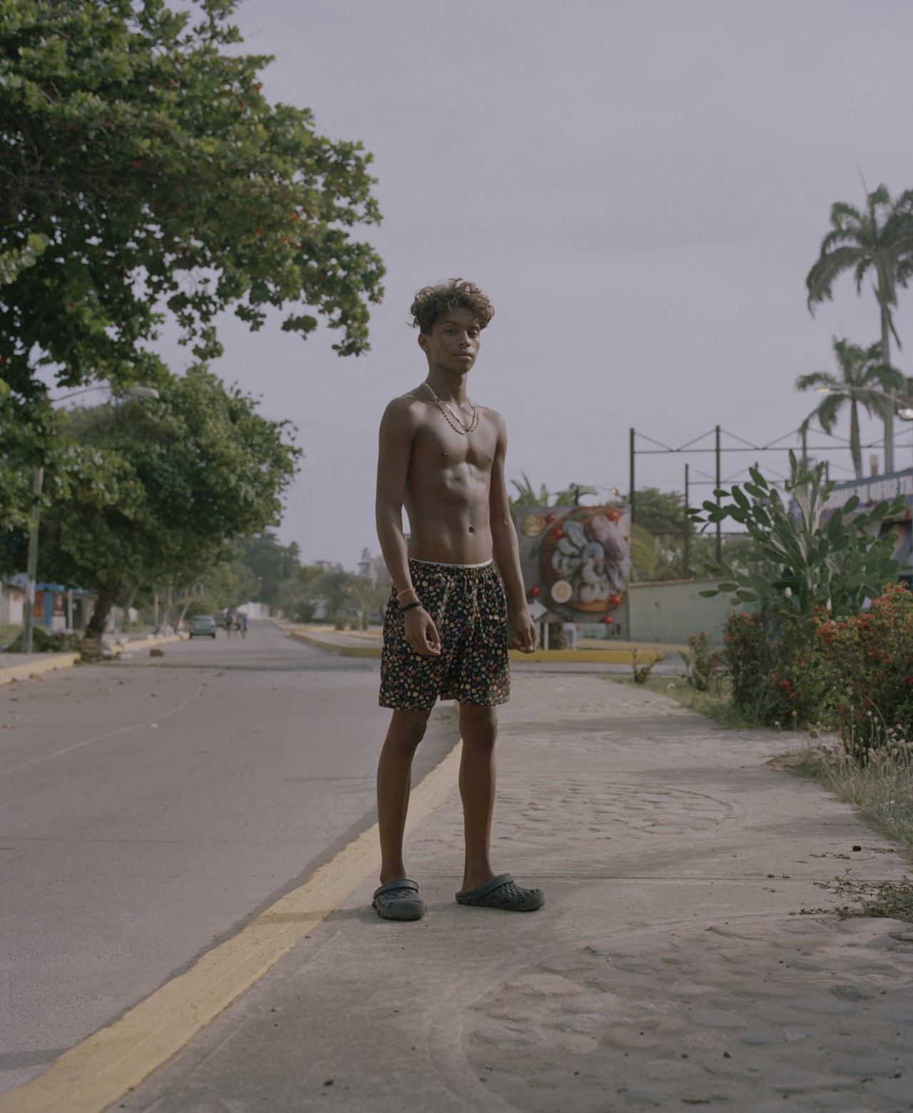 A young man from Venezuela stands on a road.
