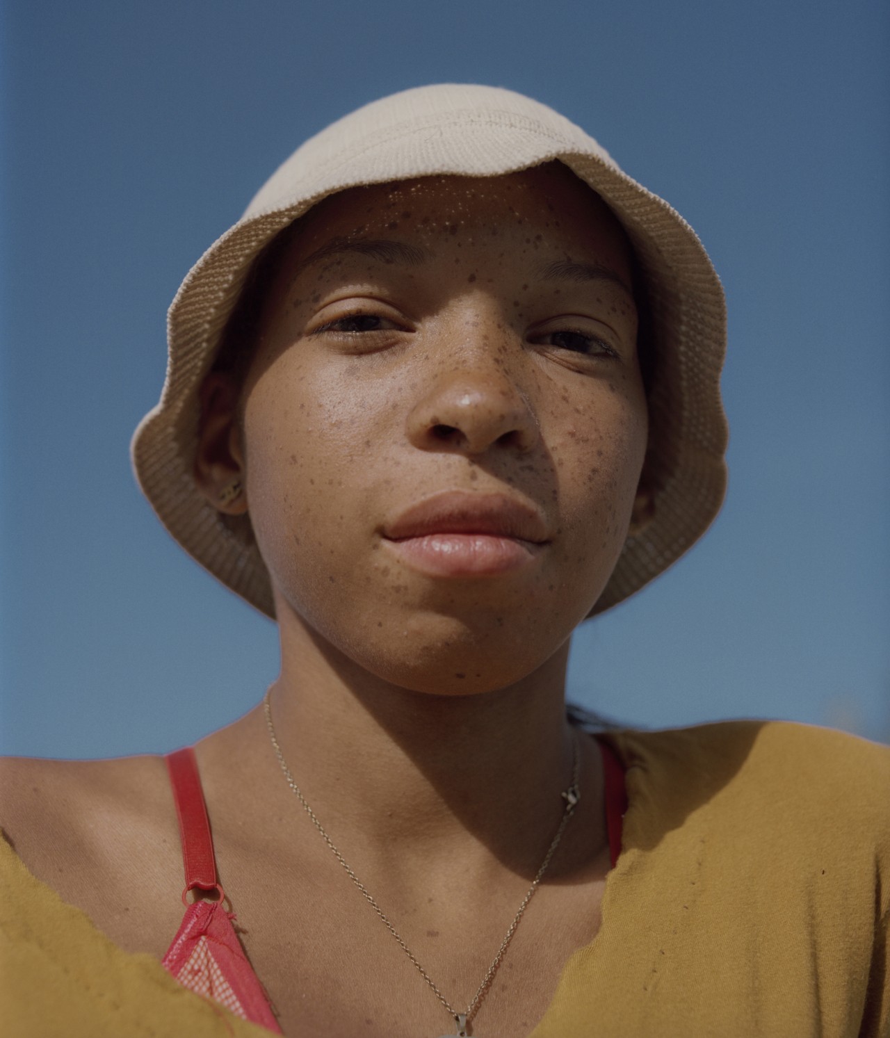 A young woman from Venezuela wearing a hat stares into the camera.