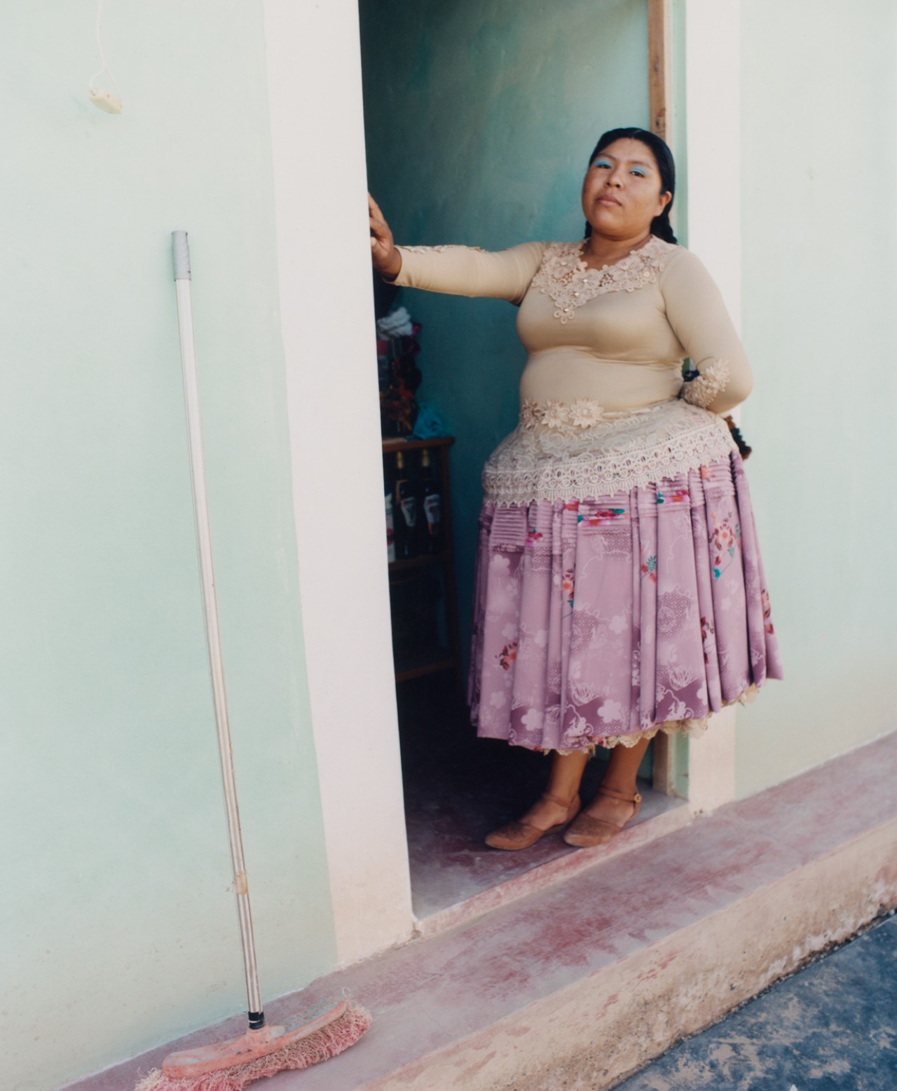 Lourdes Gutiérrez standing in the doorway, wearing lilac polleras.
