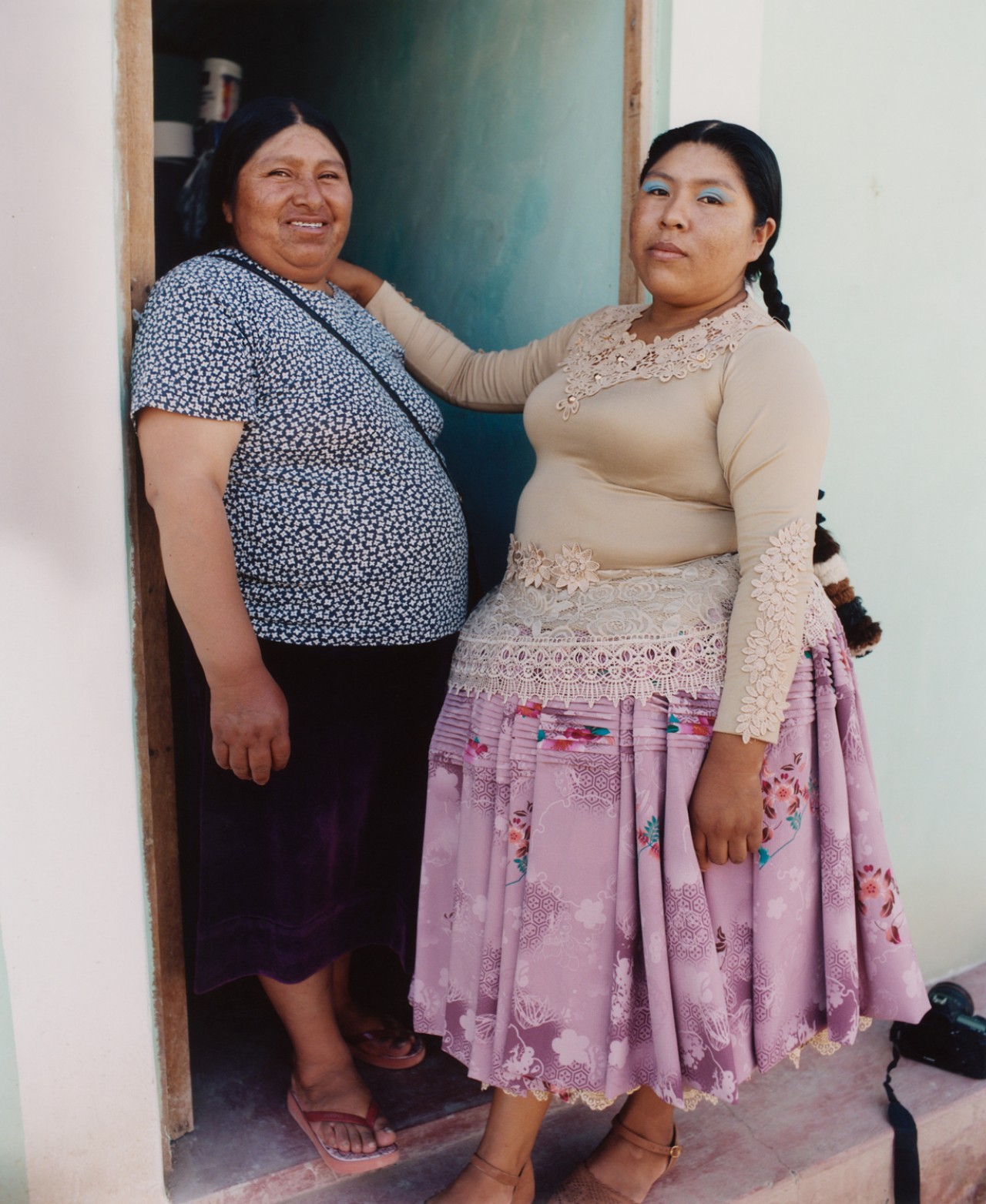 Lourdes Gutiérrez standing in the doorway, wearing lilac polleras.
