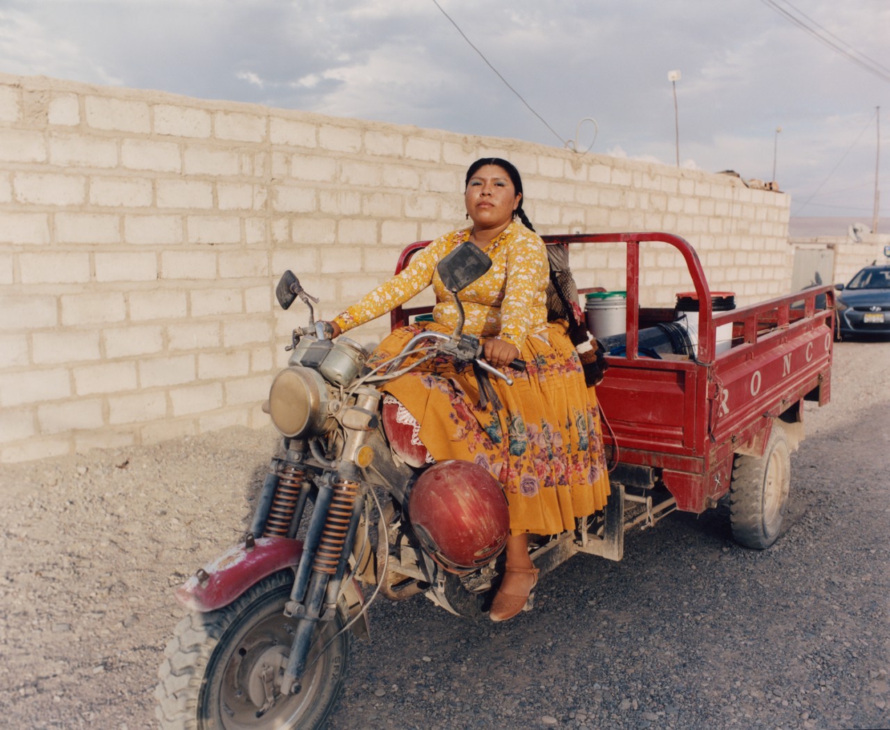 Lourdes Gutiérrez wearing yellow polleras, riding a motorbike.