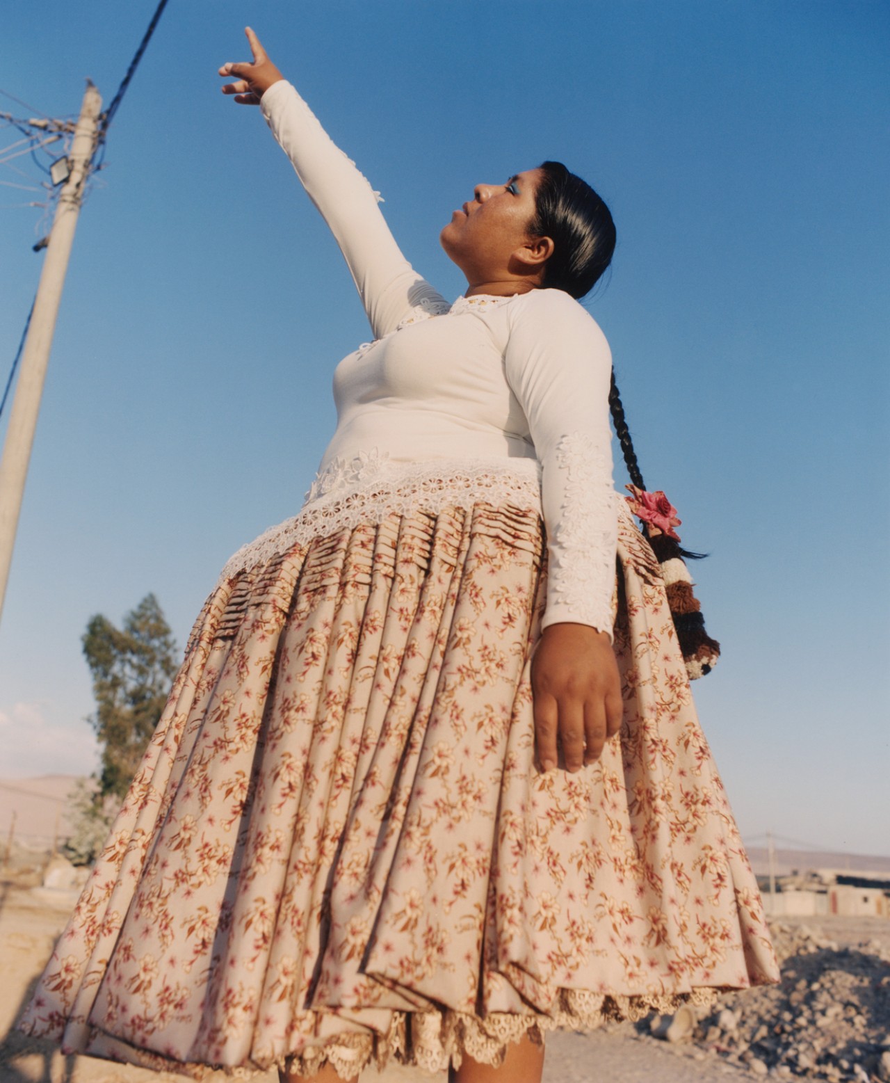 Lourdes Gutiérrez wearing floral polleras, pointing at the sky.
