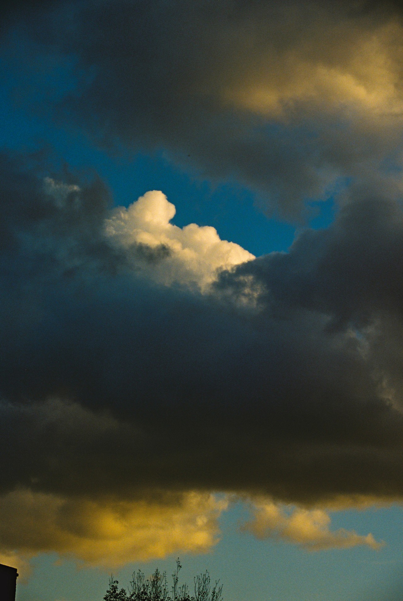 Dark clouds cover white fluffy ones in the blue sky.
