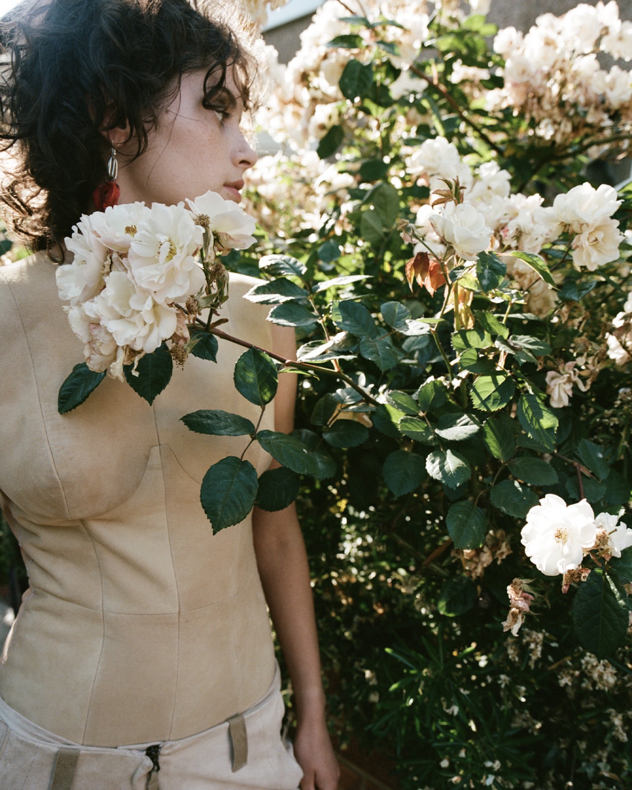 A model wearing Ponte brand poses in front of a bush of pink flowers.