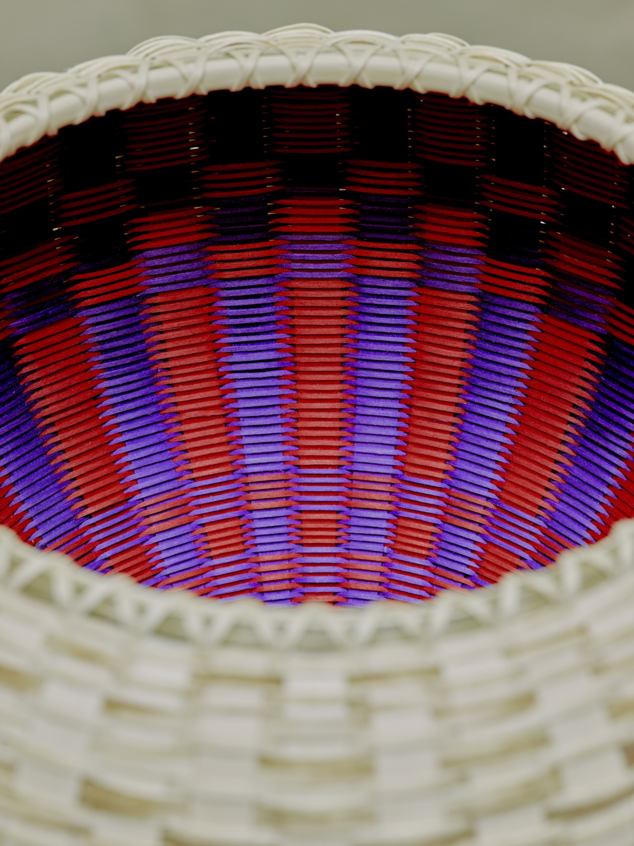 The inside of a beige basket is colored in a purple and red pattern.