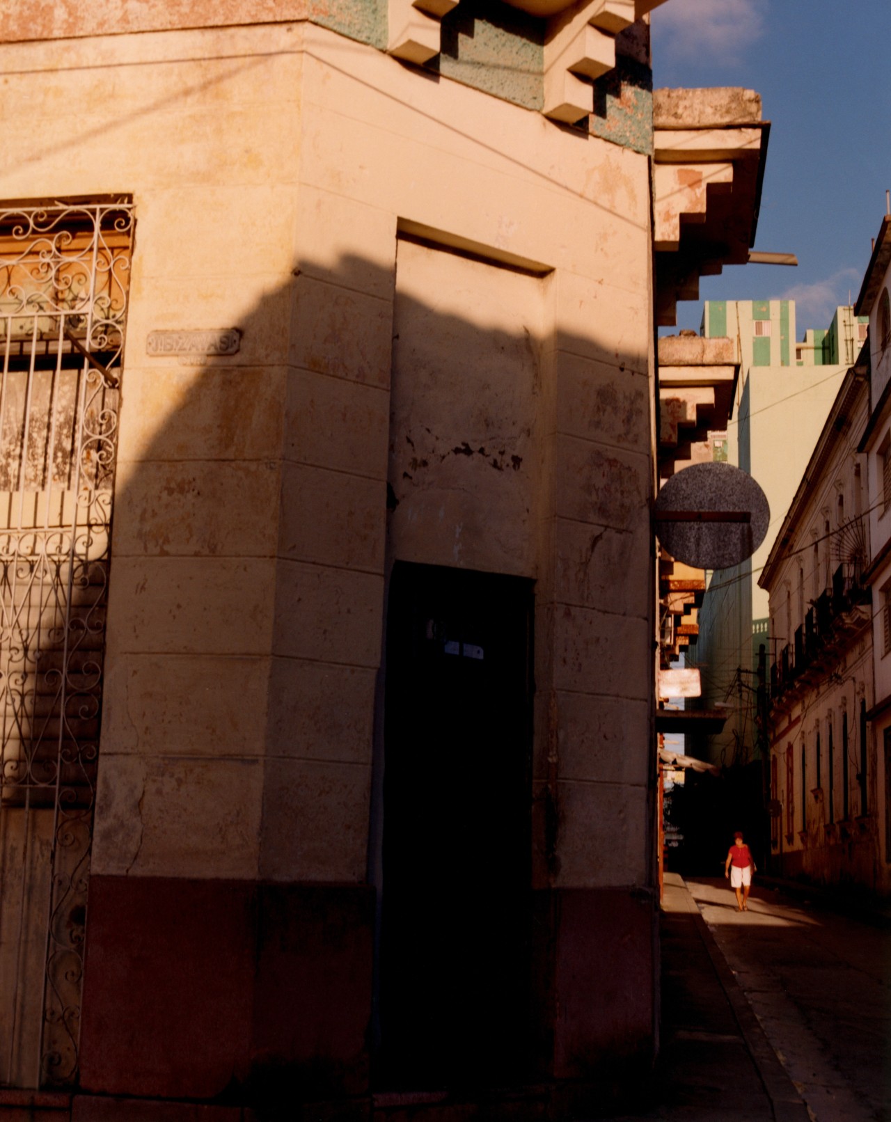 The side of a building in Cuba is shown halfway in the shadows and halfway in the sun