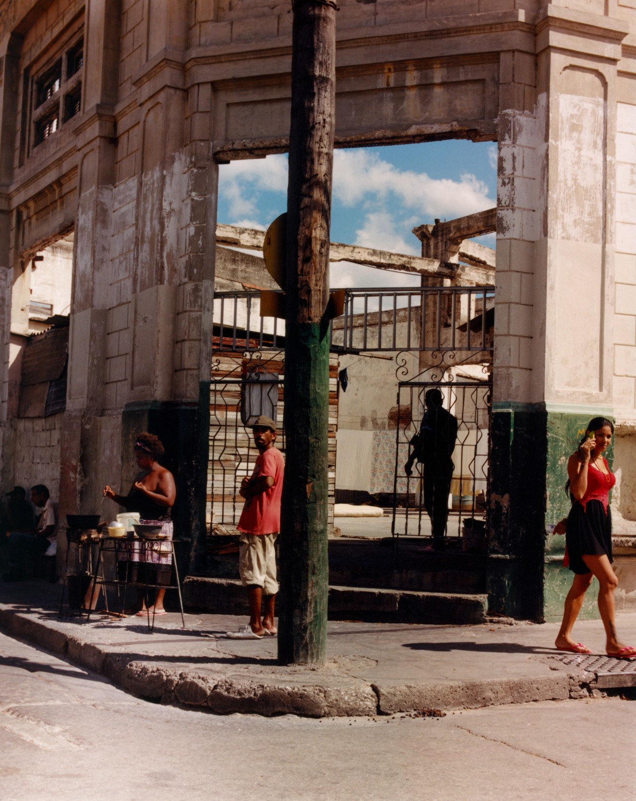 Several people stand on the corner sidewalk of a Cuban city/