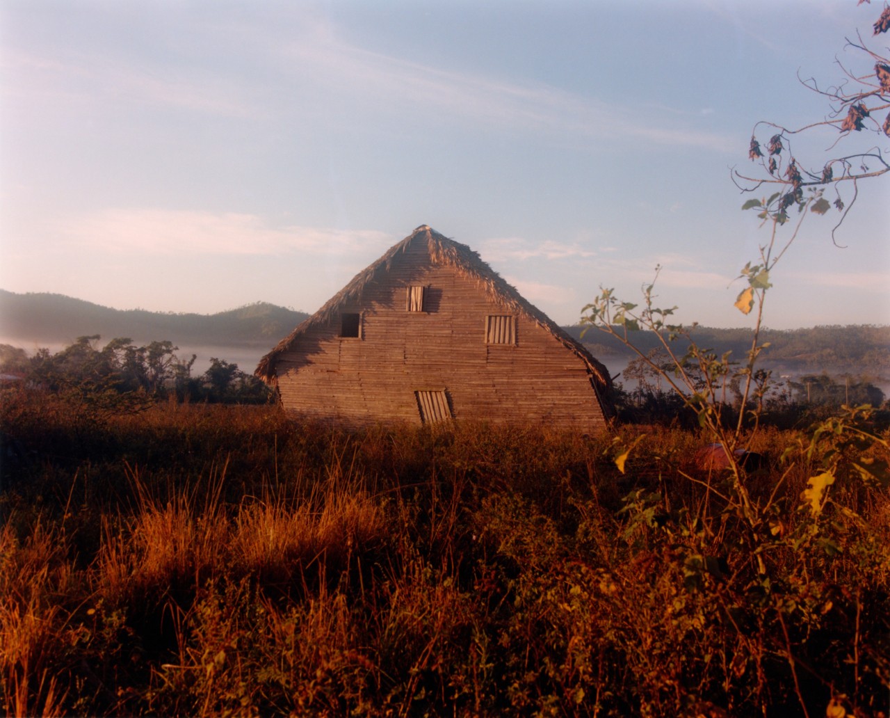 A wooden house leans slightly to the left in a field in Cuba.